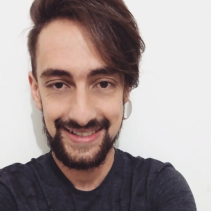 Foto do autor, Sérgio Júnior, sorrindo, com uma barba curta e camisa preta.